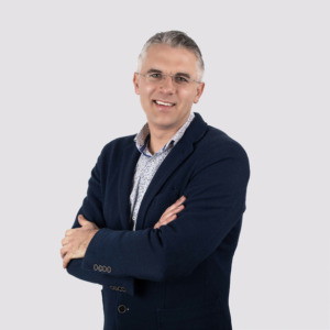Dr. Ainius La&scaron;as stovi &scaron;viesiame fone su sukryžiuotomis rankomis, vilkintis juodą &scaron;varką ir &scaron;viesius mar&scaron;kinius. Jis yra projekto mokslo darbuotojas, politikos mokslų daktaras.